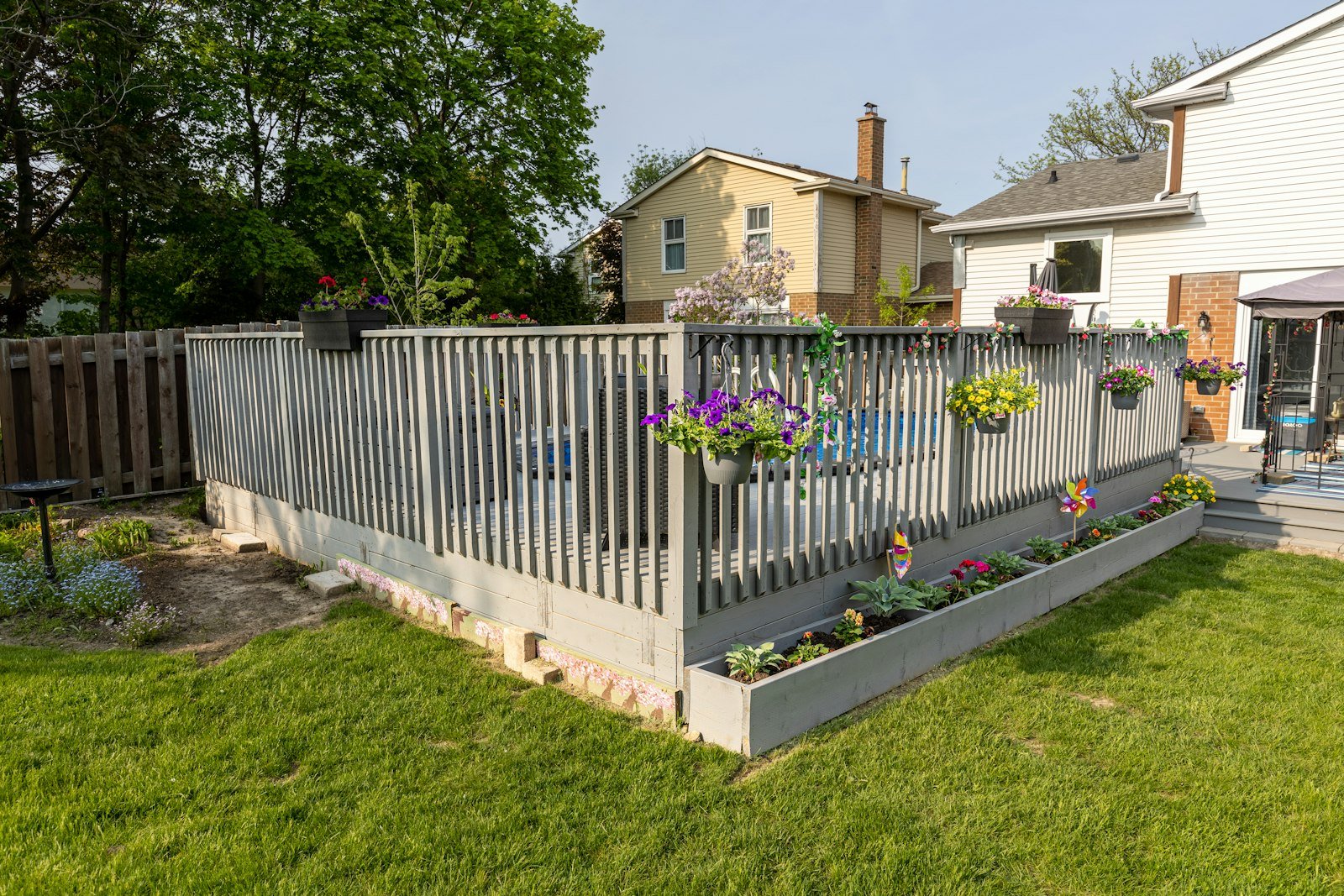 Trimmed backyard lawn beside a wood deck and fence line.